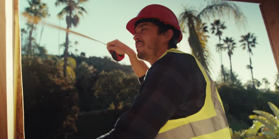 A construction worker is measuring the frame