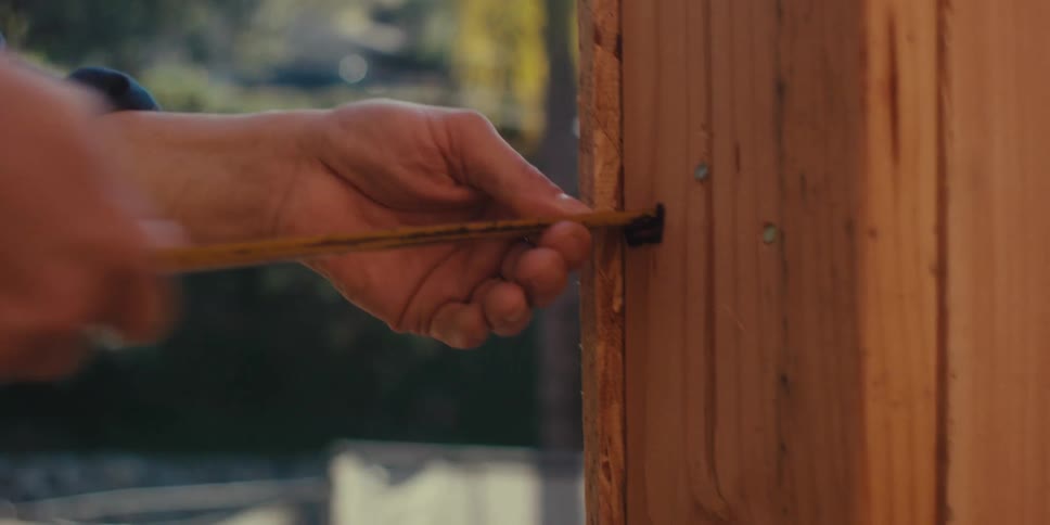 A construction worker uses a tape to measure the distances on a framework