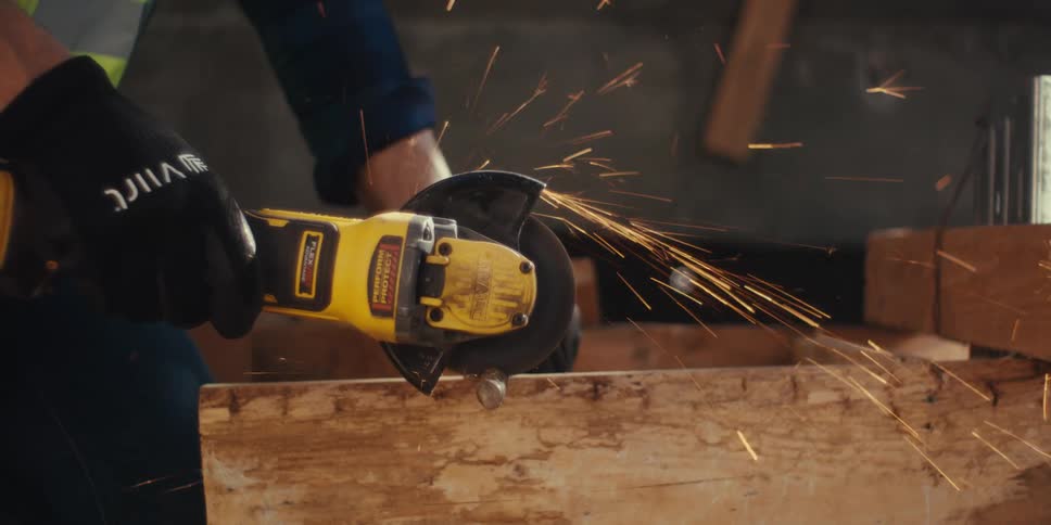 A construction worker sands down a wooden project he is working on