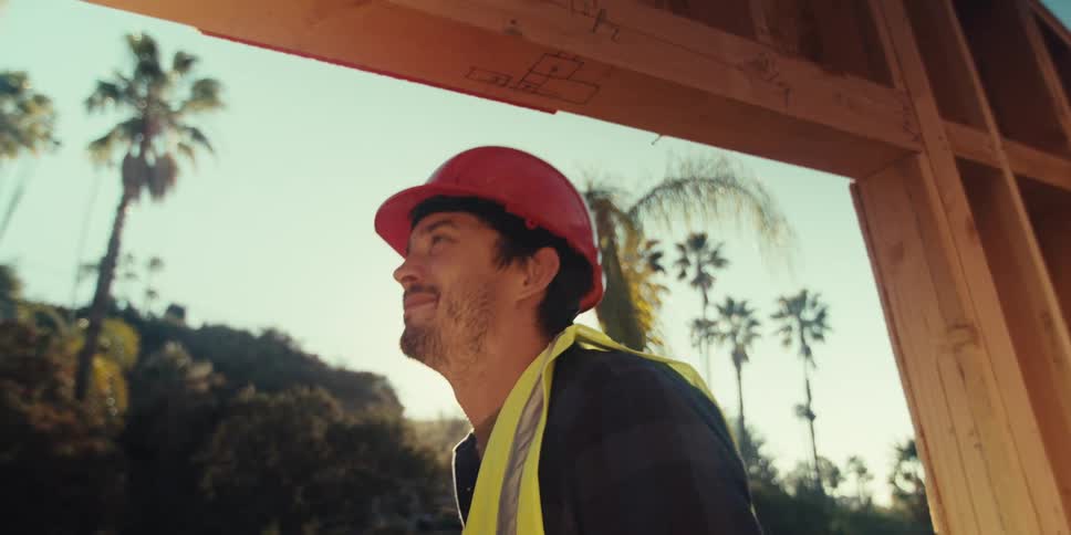 Male carpenter makes measurements while working on a construction site on a sunny day