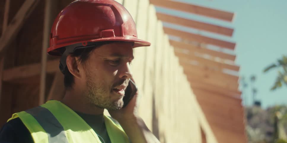 Contractor on a job site having a conversation on a cell phone