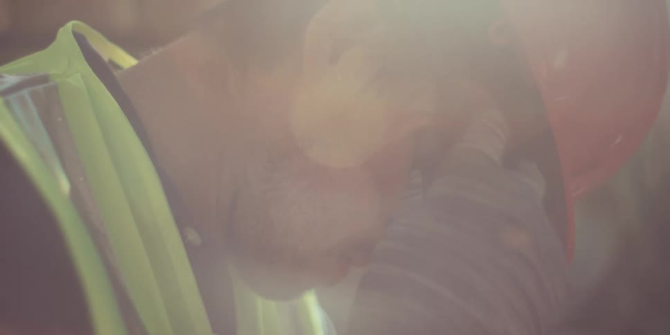 Man wearing a protective helmet operating a cutting tool emitting sparks on a construction site