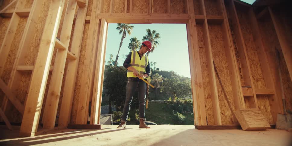 Man measuring the opening of a door with a tape measure at a construction site