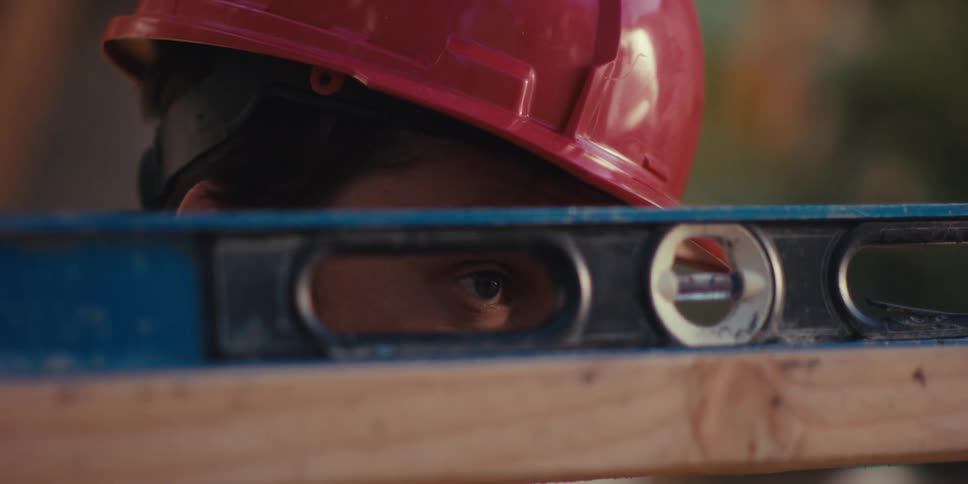 A construction worker is making sure the wood is level