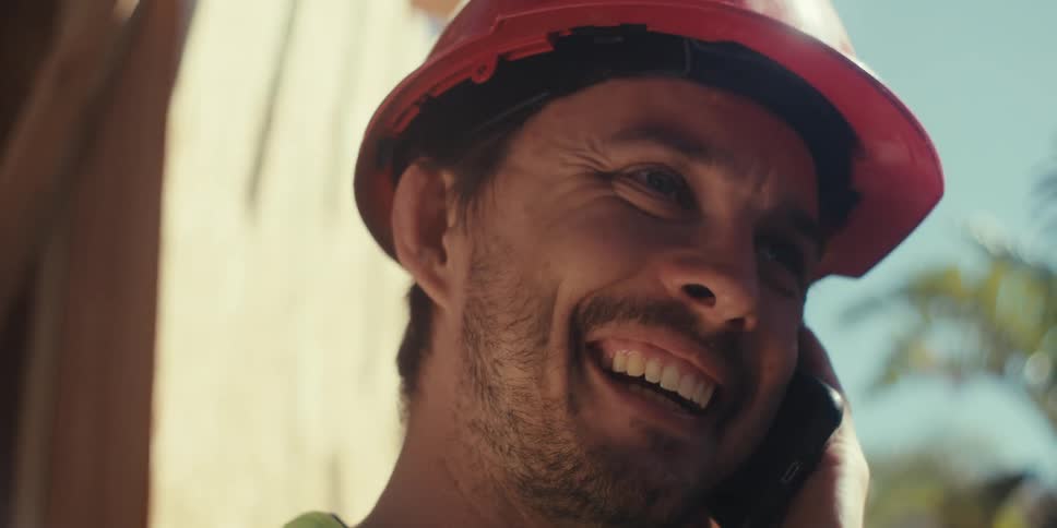 Construction worker is laughing while talking on the phone with someone