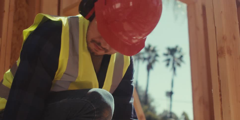 Man wearing a helmet and vest working on a construction site in the early stages