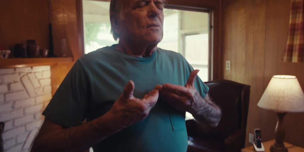 Elderly man is doing a series of stretches inside of his home
