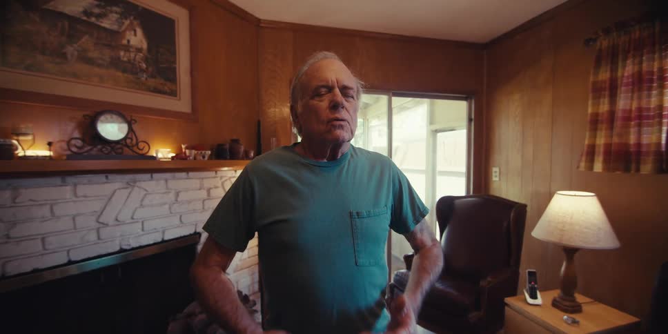 Elderly man standing in a living room taking deep breaths in yoga position