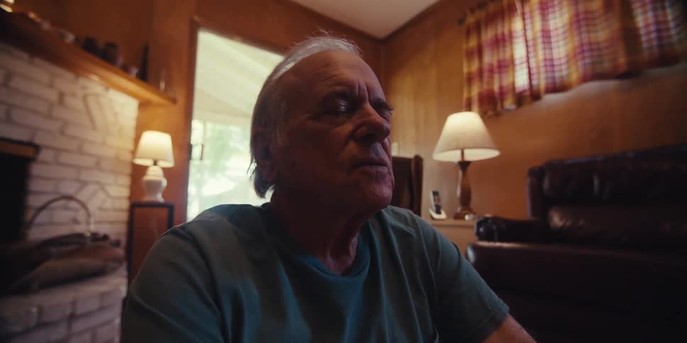 Elderly man sitting on a yoga mat in the living room meditating