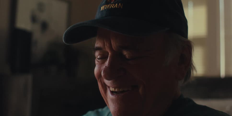 Elderly man laughs while alone at home
