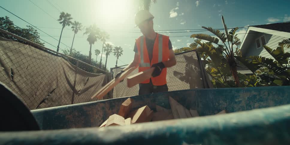 A construction worker is lifting lumber