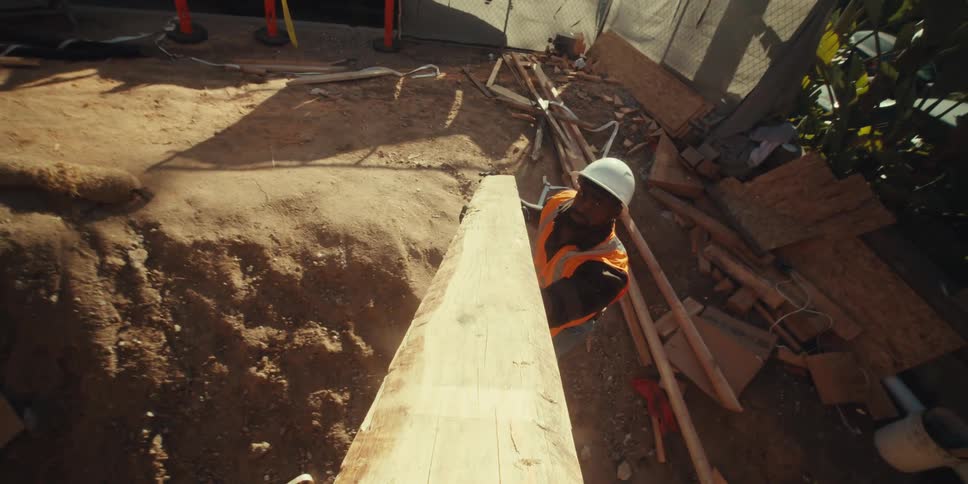 Construction workers pass wood to one another