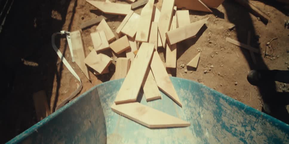 Workers empty wood from the wheelbarrow together