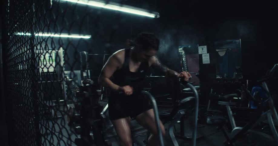 Woman pedals on a stationary bike in an empty gym