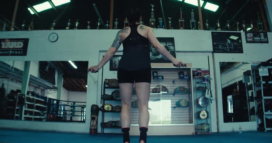 Woman from behind jumping rope in a boxing gym