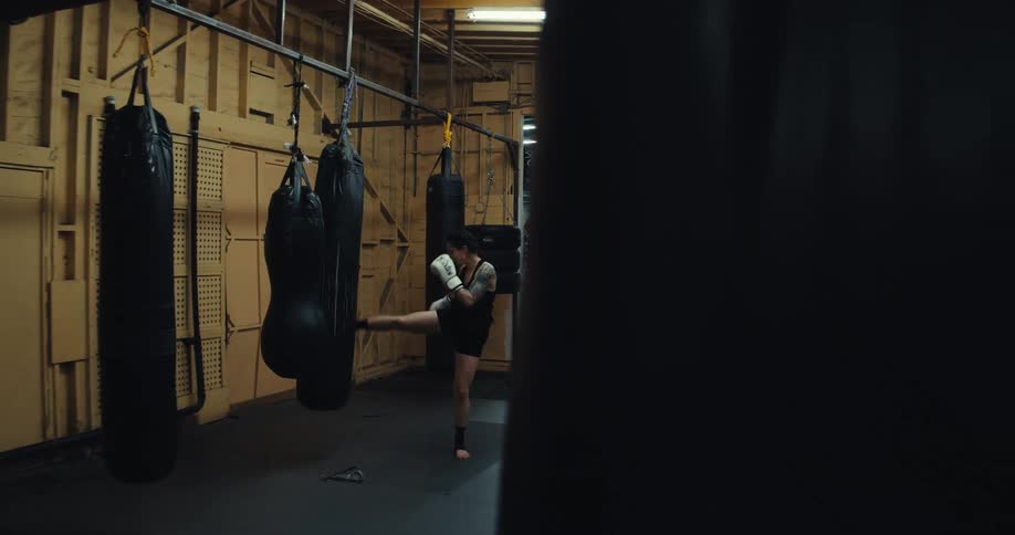 A woman is kicking and punching a bag while training at the gym