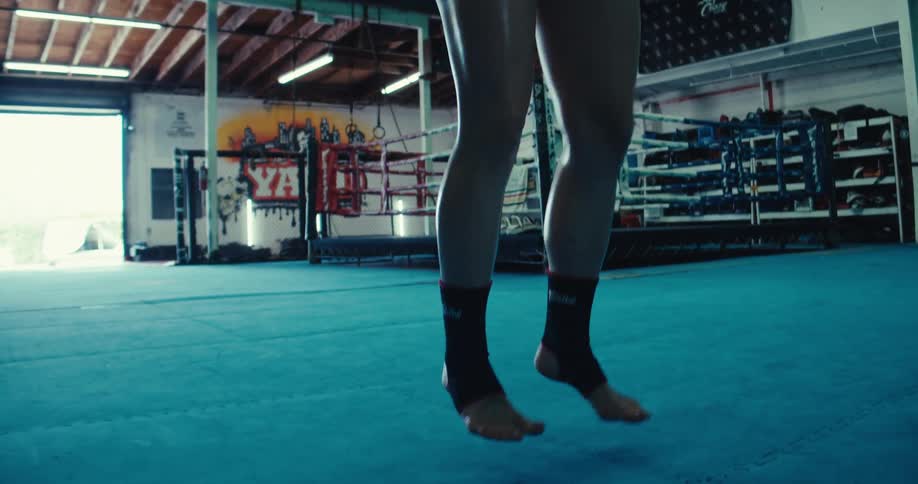 Woman jumping ropes while at a boxing gym