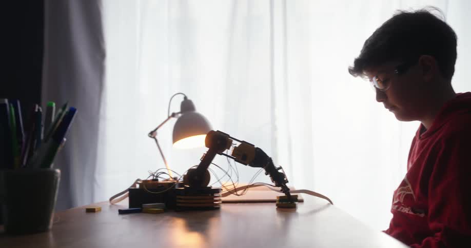 A footage of a boy watching a robot on the table