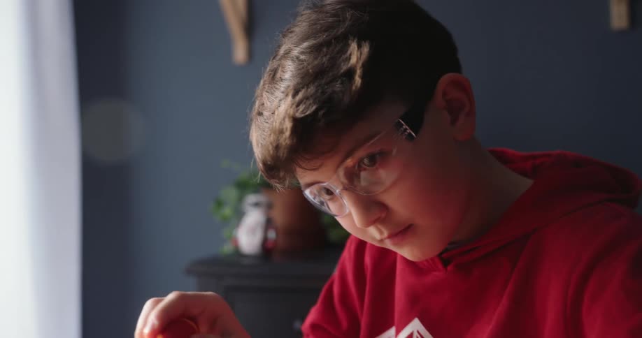 Boy works on a robot arm while sitting at a desk at home
