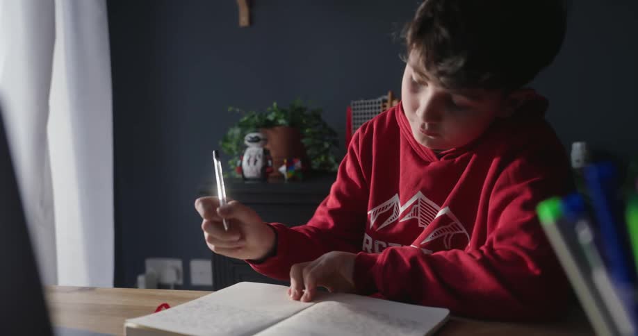 A boy is doing his homework at the desk