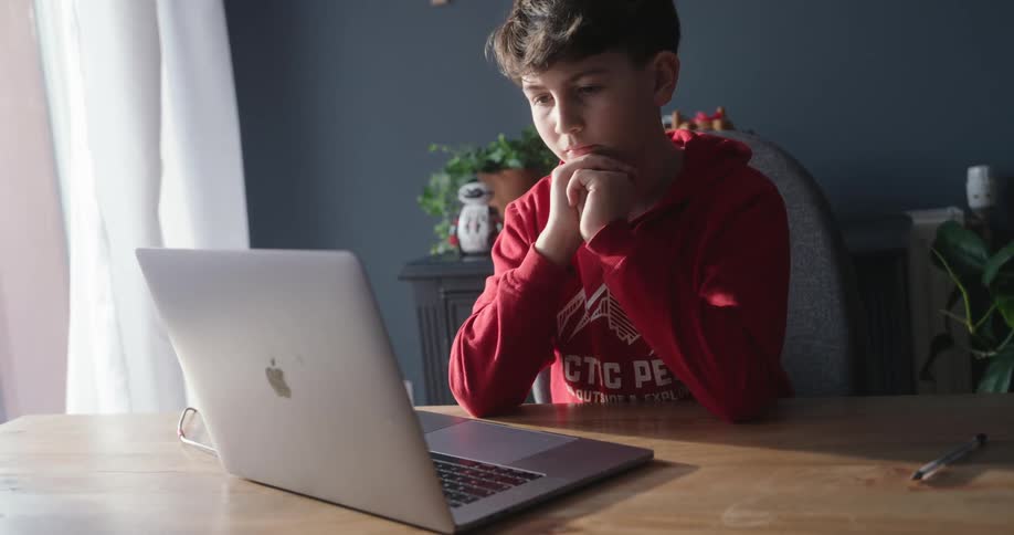 A boy typing on a laptop