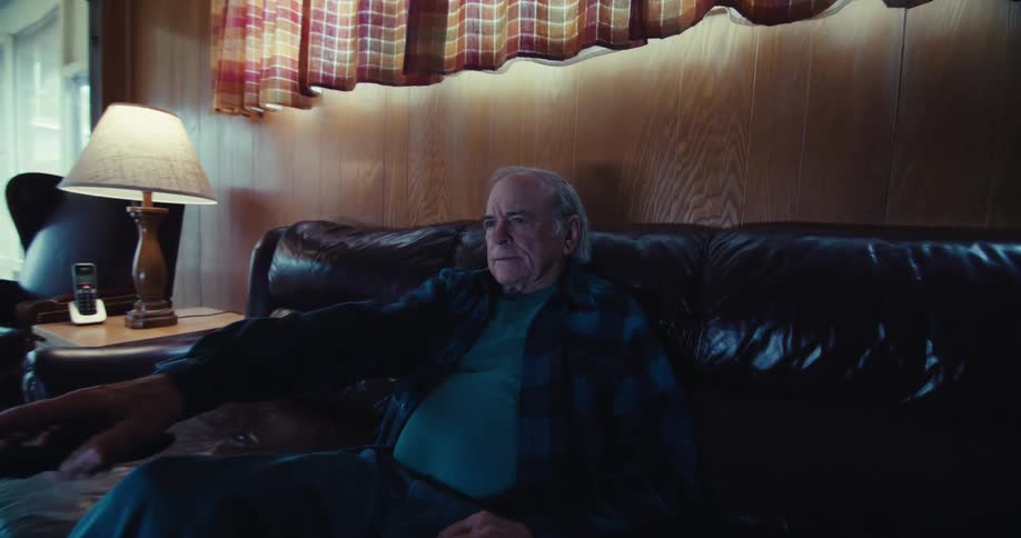 Elderly man using a television remote control