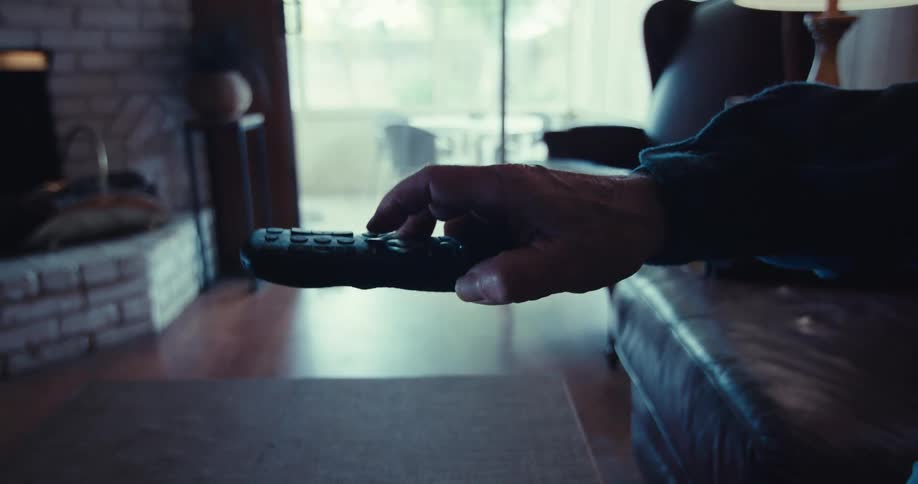 A man presses a button on the remote then puts it down