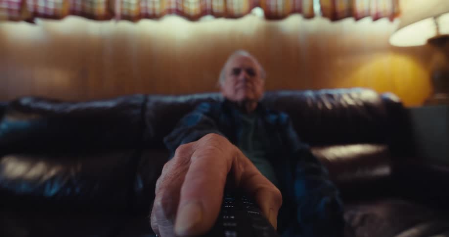 A man points the remote at the television