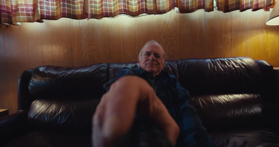 A man lifts the remote and presses a button
