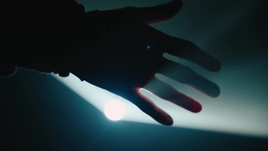 A man waving his hand back and forth in front of a spotlight