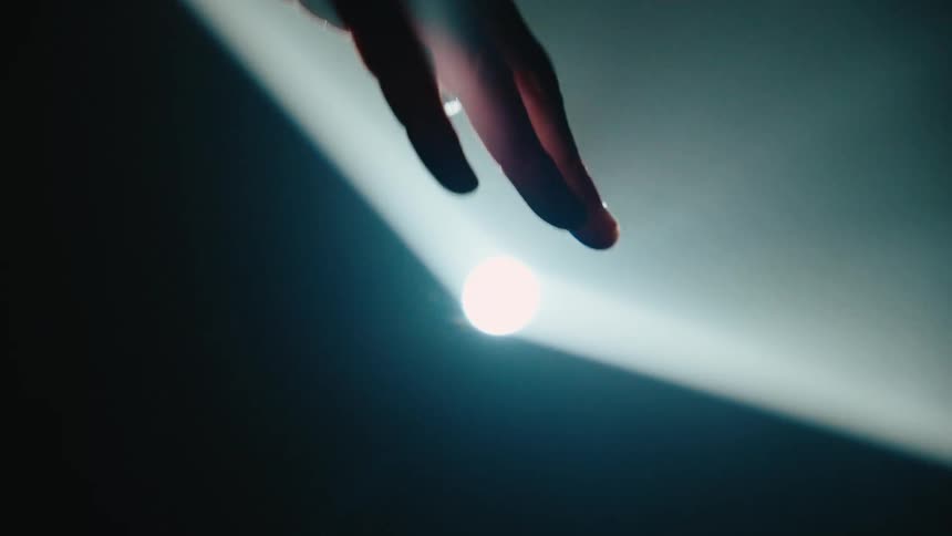 A hand moves in and out of a spotlight