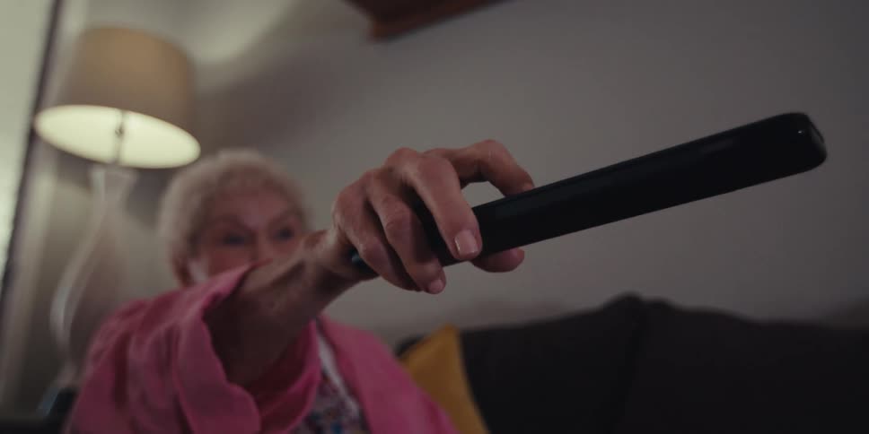 A woman points the remote at the television