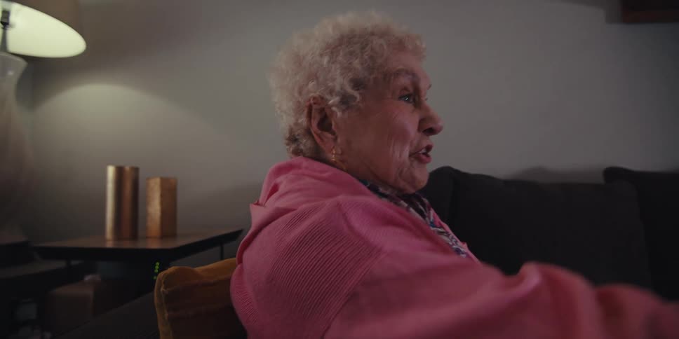 Elderly lady sitting on the sofa in the living room and interacting