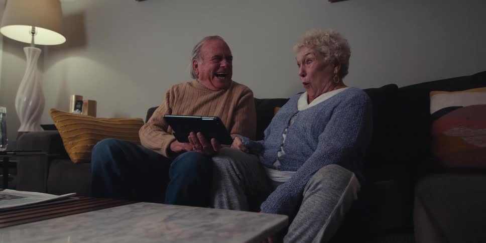 A couple laugh while looking at their tablet