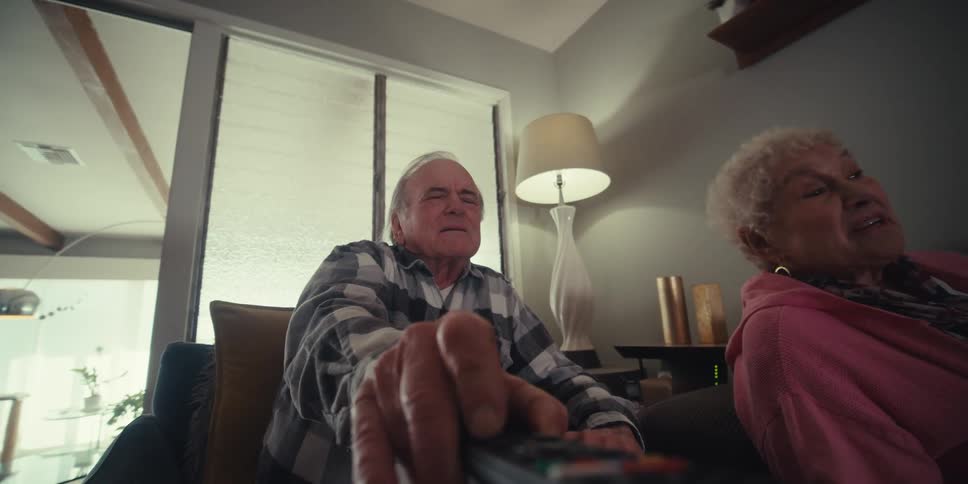 Two people talk while the man uses the television remote