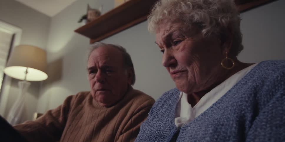 An elderly couple talking about a tablet