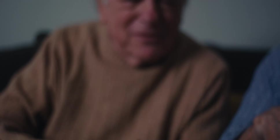 A man laughs and waves towards the tablet