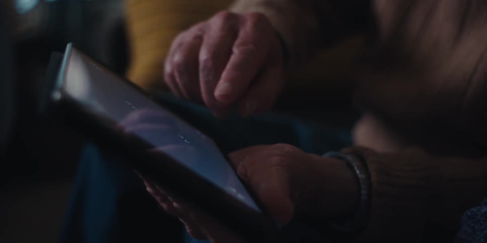Hands of two elderly people interacting with a tablet