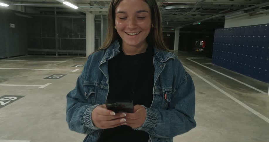 A girl is texting on her cell phone in the parking garage