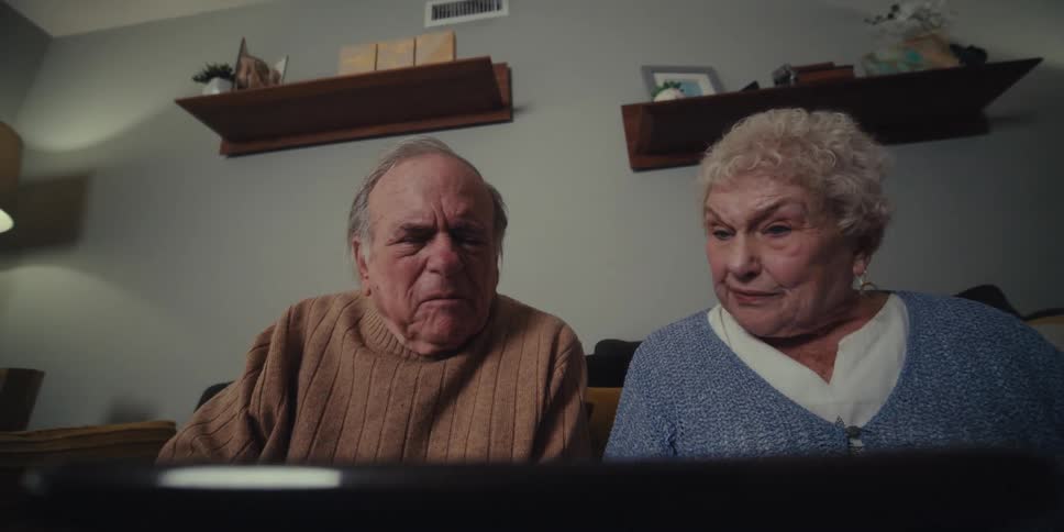Two elderly people talking and interacting with an object