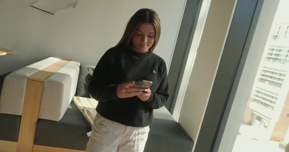 A teenager is texting by the window