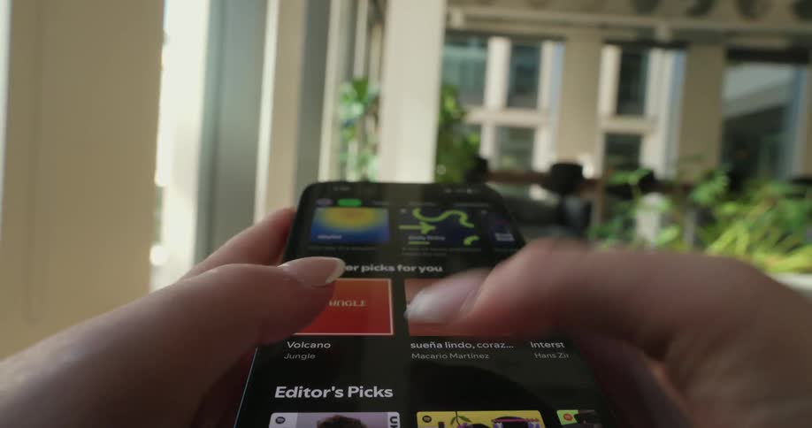 Pair of womans hands browsing spotify on smartphone