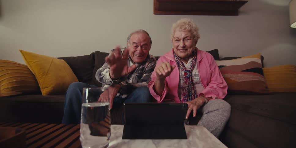 Cheerful elderly couple waving goodbye on a video call on a tablet