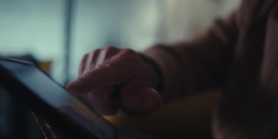 Two older people discuss a tablet while sitting in a living room
