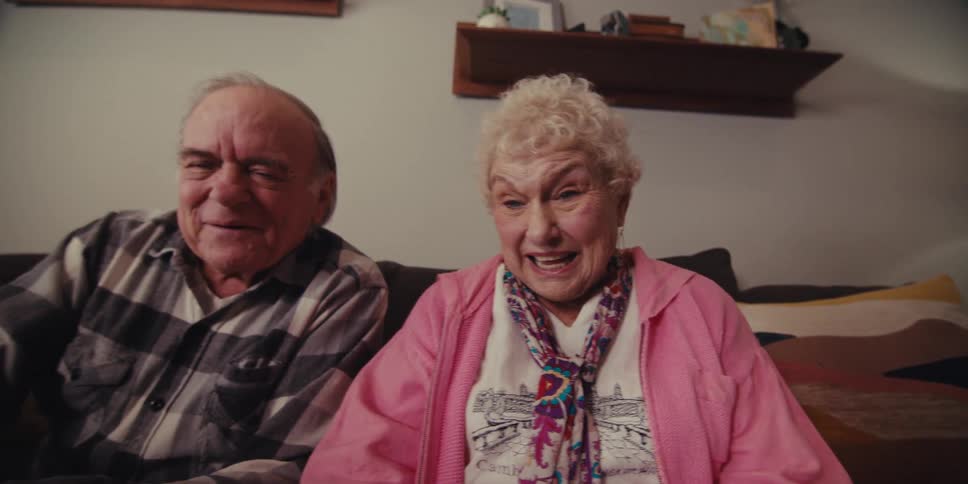 A man and woman are talking and laughing on the couch