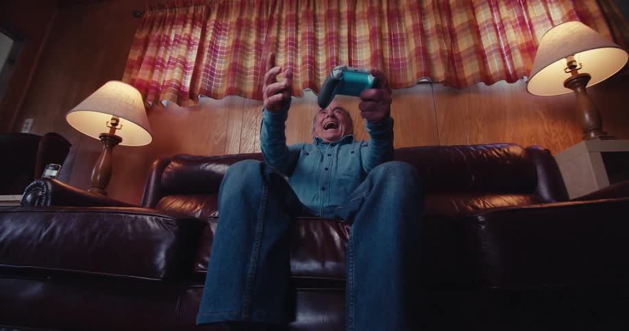 Elderly man cheering and getting happy while holding a wireless video game controller