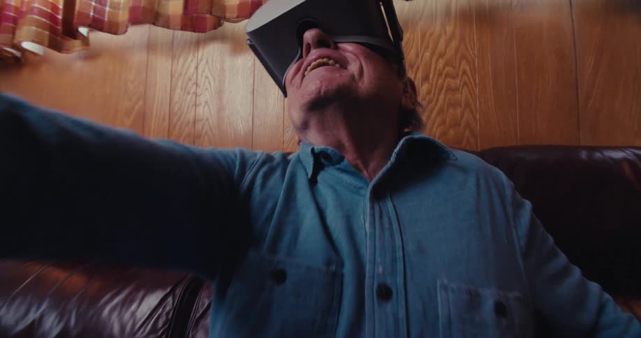 A man is smiling and swinging a controller while using virtual reality