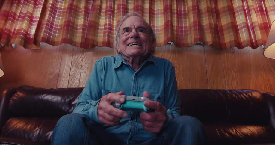 A man leans forward with the controller while playing video games