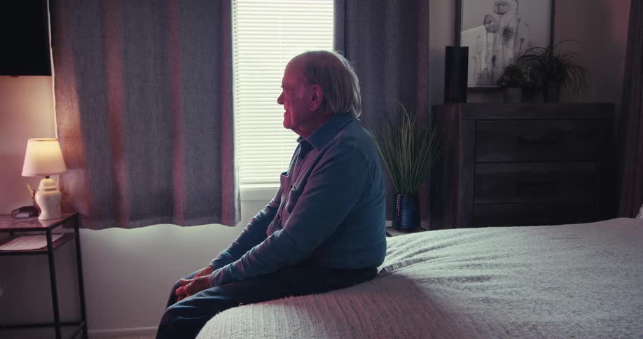 A man slaps his legs and laughs while watching television