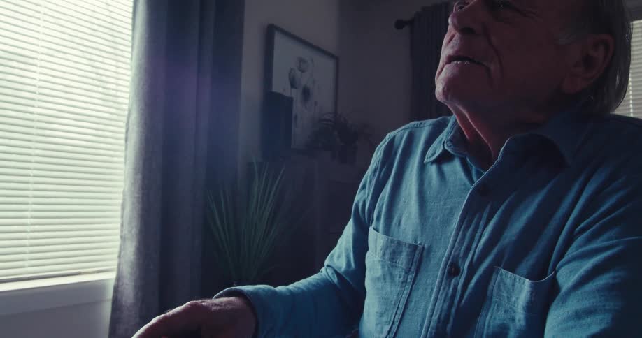 Elderly man trying to change channels on tv with a remote control